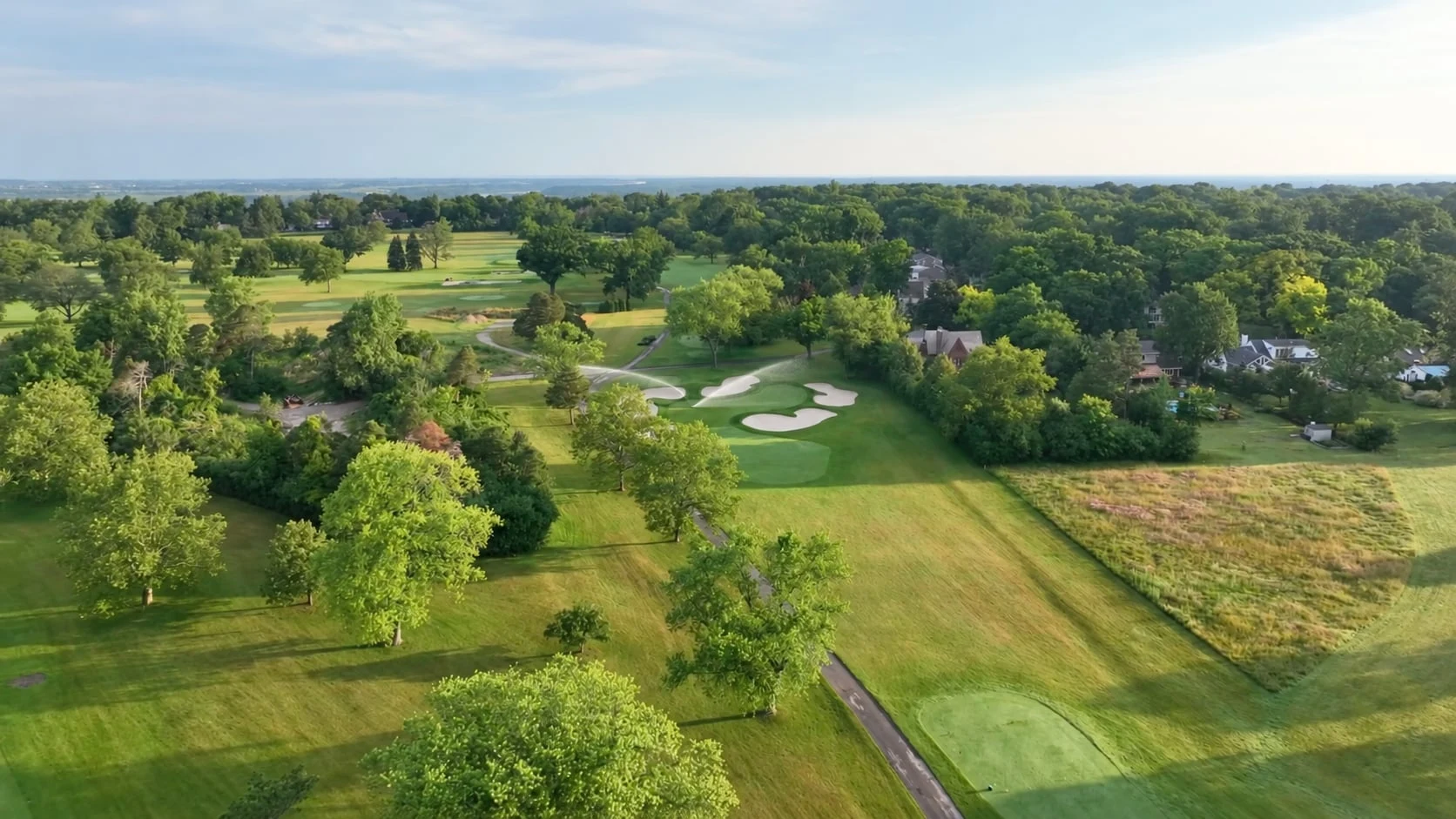 Source-based aerial view of Niagara Falls Country Club’s bunker-lined small green with one illustrative paired irrigation spray at its left edge.