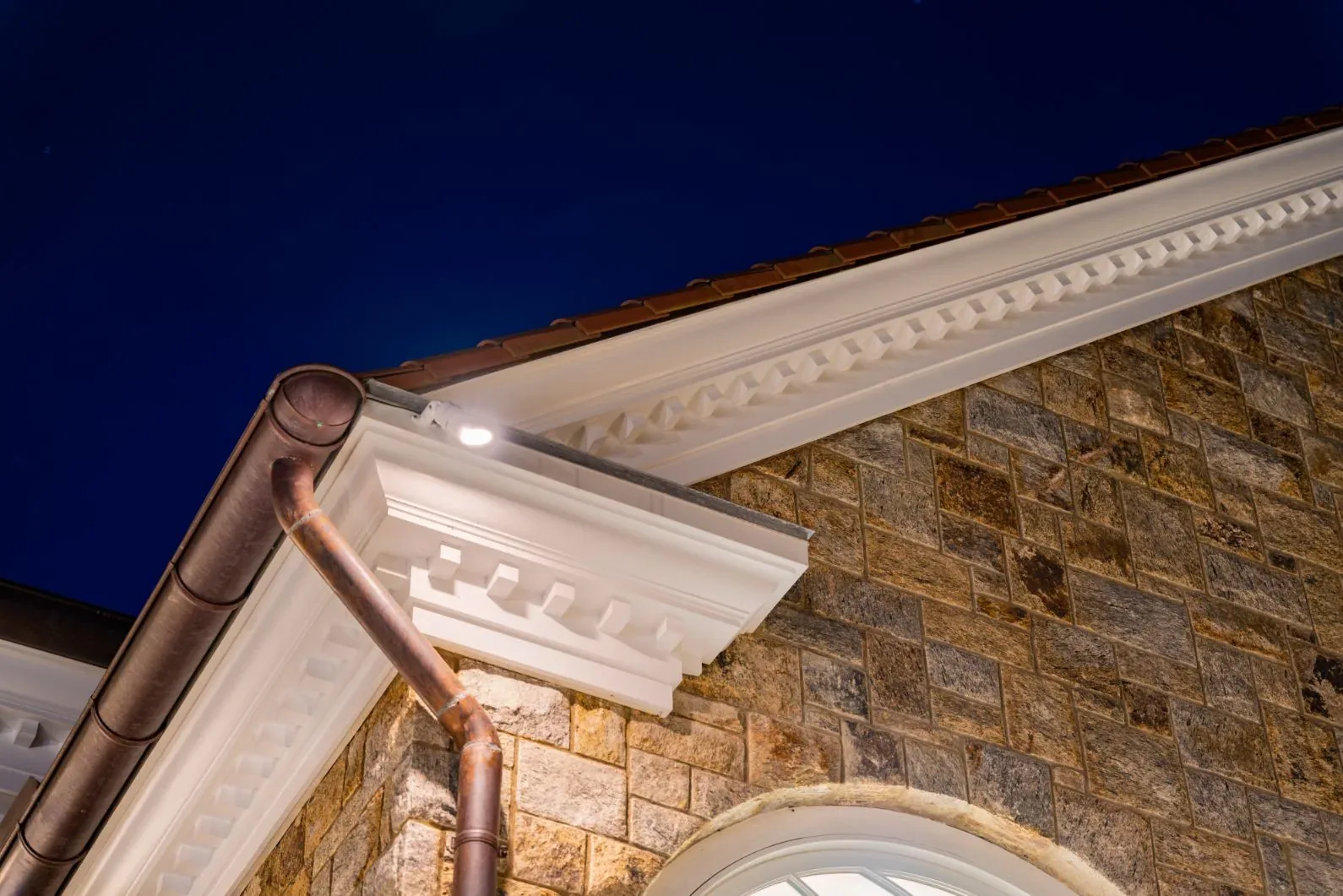 Close view of lighting beneath the eaves of a stone house.