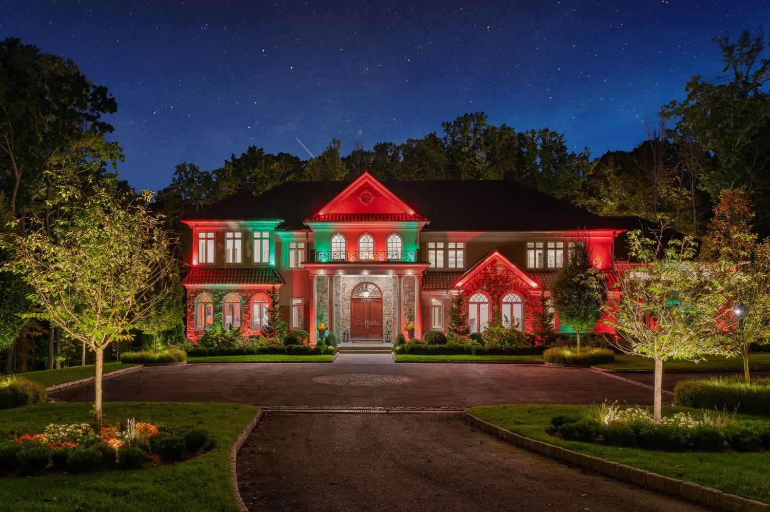 House facade illuminated in red and green at night.