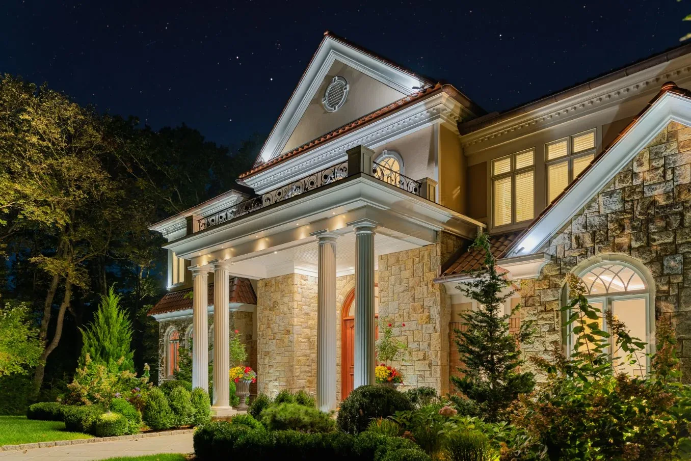 White trim and stone facade of a house illuminated at night.