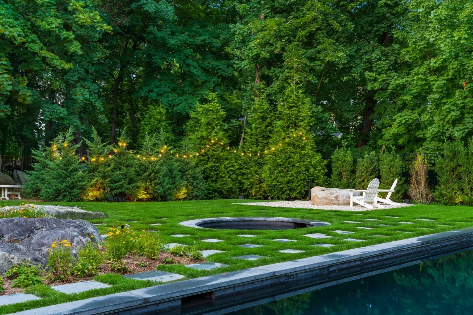 Stepping stones, circular spa, and chairs beside a swimming pool in daylight.