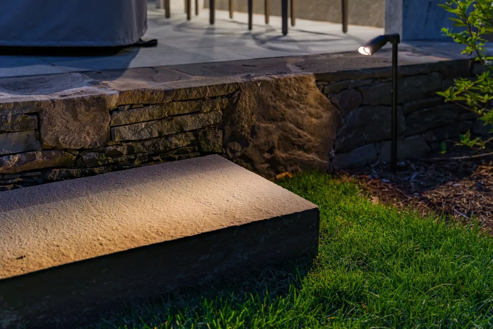 Light directed onto a stone step beside a raised patio.