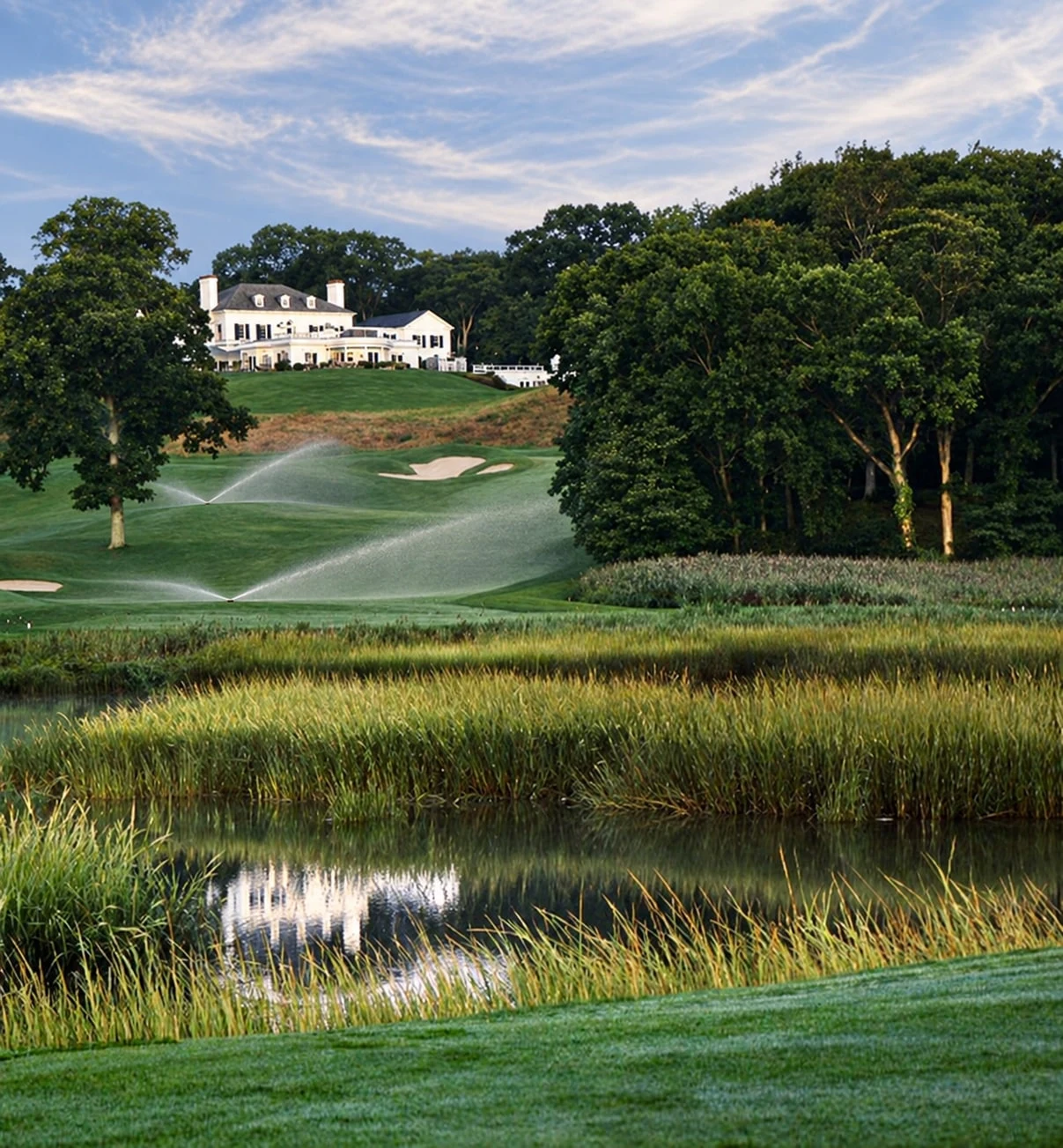 AI-edited view of Nissequogue Golf Club’s clubhouse and fairway across the marsh, with irrigation added.