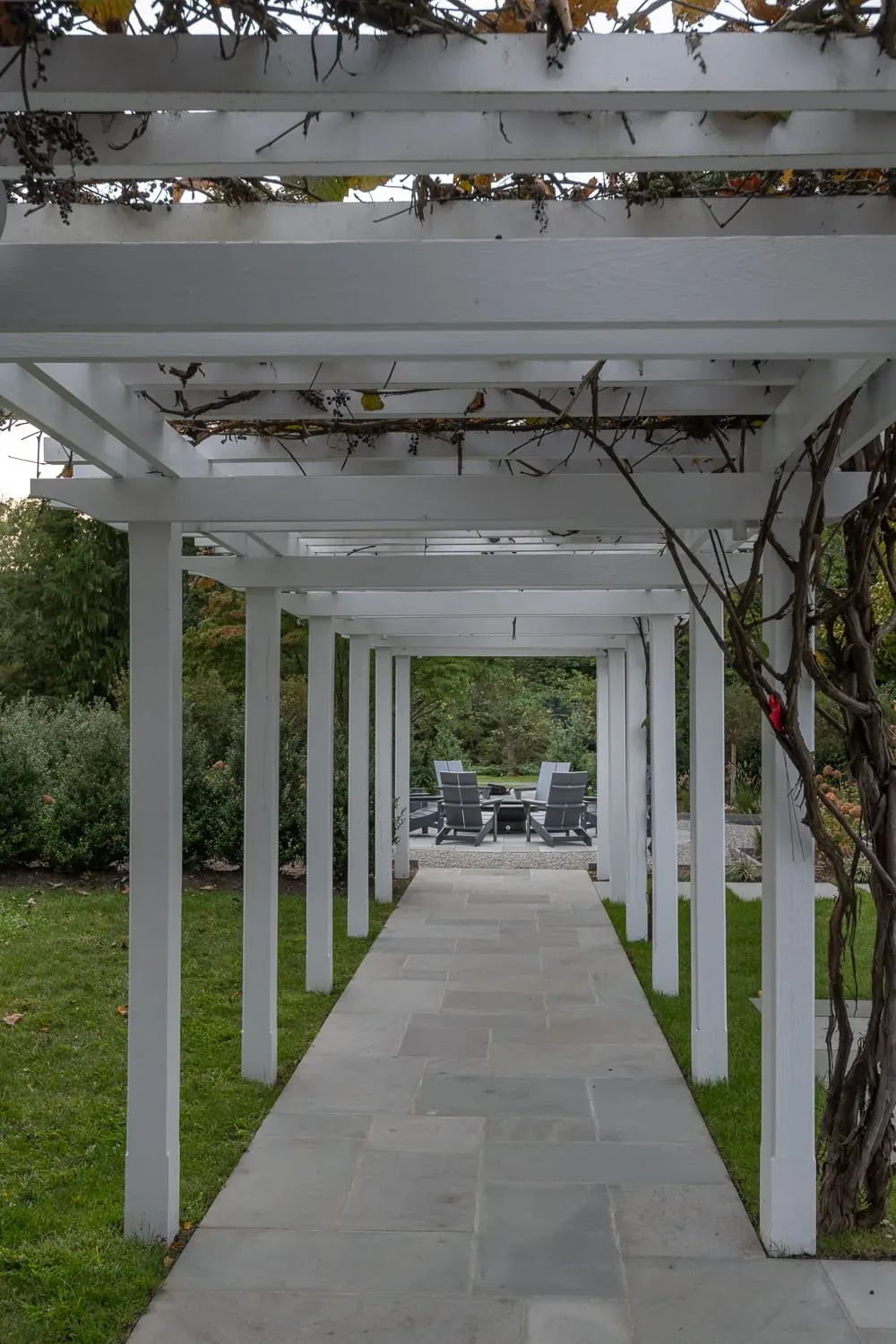 Stone path running beneath a long white pergola during the day.