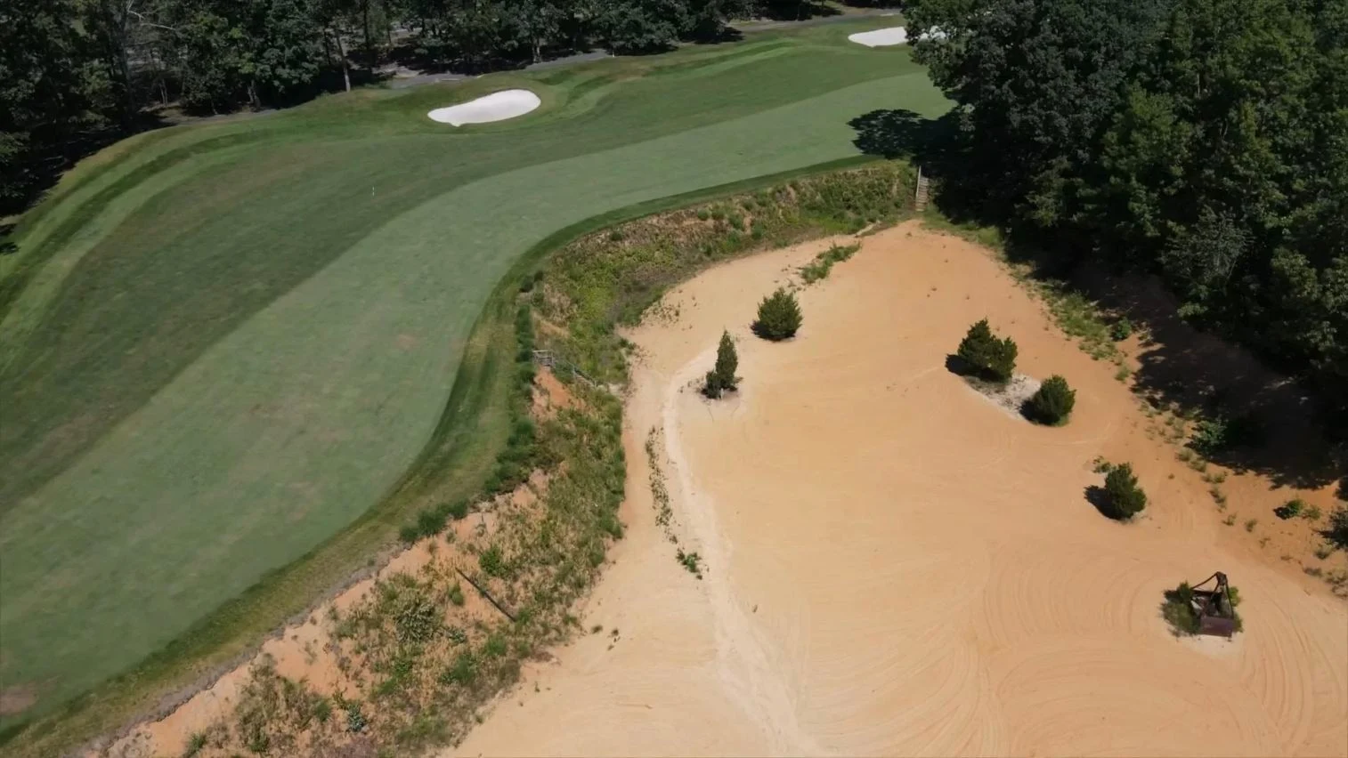Oblique aerial fairway beside orange sand quarry, five pines and historic machinery. Original view of Scotland Run Golf Club.