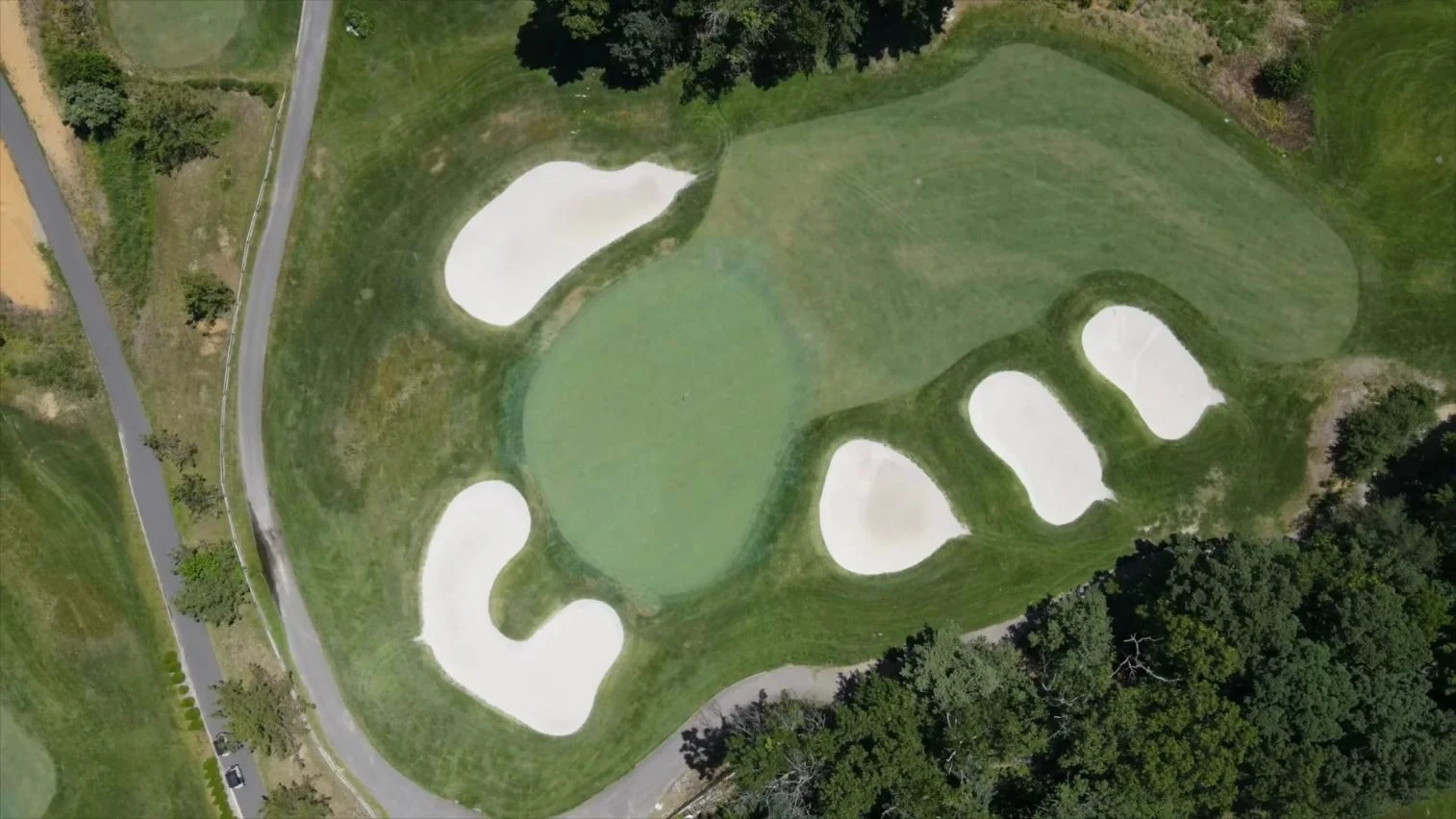 Steep overhead of green enclosed by five distinct white bunkers; cartpath left and bottom. Original view of Scotland Run Golf Club.
